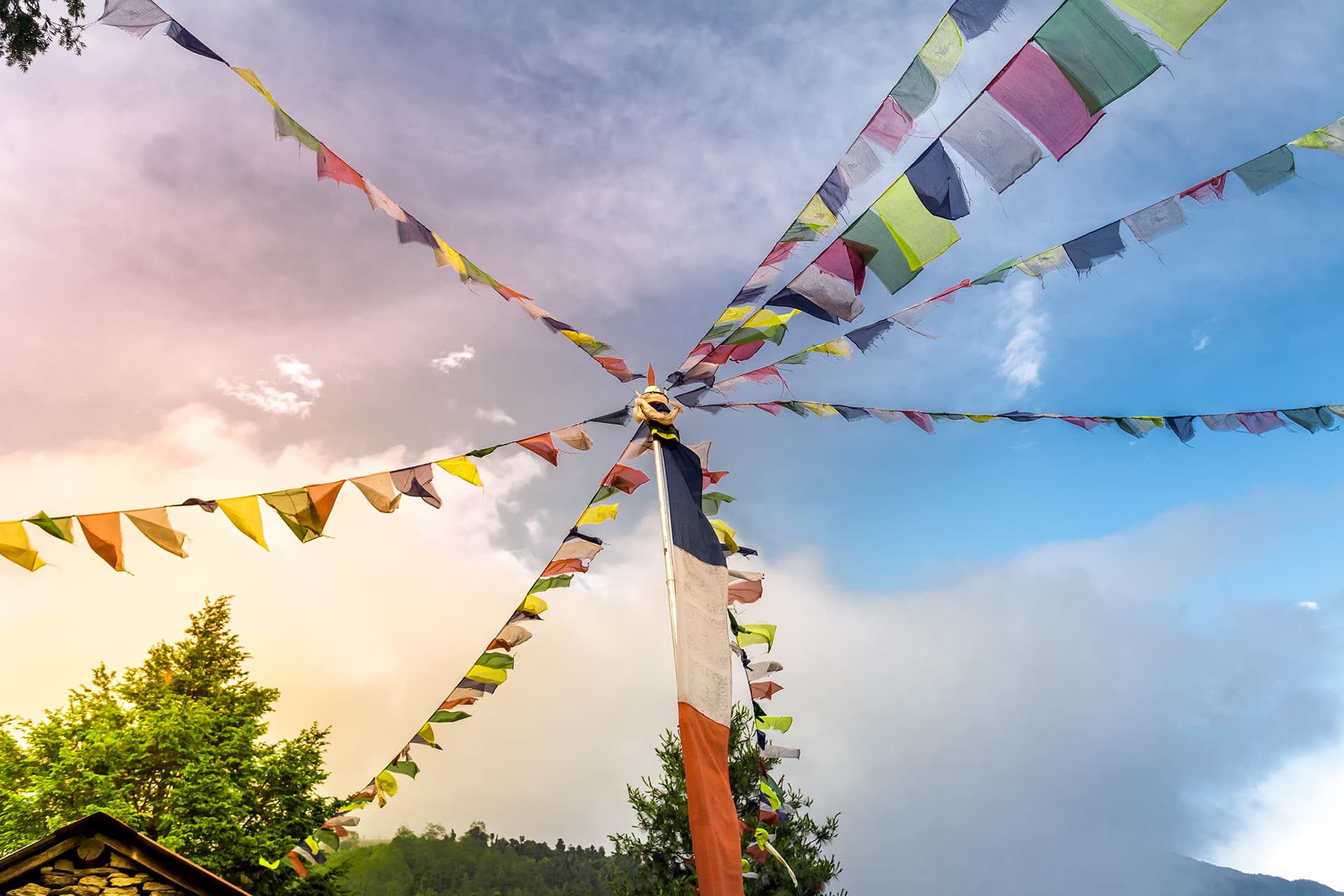 Buddhist tibetan prayer flags against blue sky with a cloud. Many colorful waving flags suspended between trees